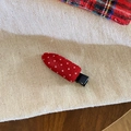 Close-up of red and white polka dot hair clip on a textured fabric background - Traceless Style