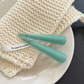 Detailed view of light green acetate hair clips on a textured knit pot pad holder - Cyan