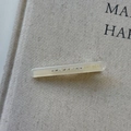 Close-up of cream acetate hair clip with small rhinestones on a linen texture background - White