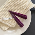 Detailed view of two handmade deep purple acetate hair clips on a white ceramic tray - Deep purple