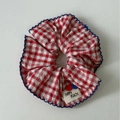 Detail van rood-blauwe gingham scrunchie met geschulpte randen en Happy Peach-logo - Rood Gingham Scrunchie