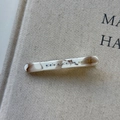 Close-up of marble acetate hair clip with colorful rhinestones on a beige textured fabric - Milk Coffee