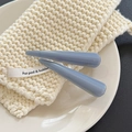 Detailed close-up of blue acetate hair clips with gold lettering on a soft knitted coaster - Haze Blue