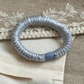 Elegant silver grey satin scrunchie with pleated texture and soft blue buckle detail - Blue