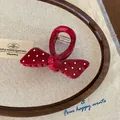 Dettaglio di un fermaglio per capelli vintage rosso a pois su una cornice di legno - Stile Fiocco