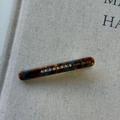 Macro shot of tortoiseshell acetate hair clip with crystal studs and gold branding - Blue Brown Gradient