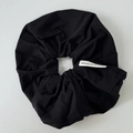 Detail of black cotton scrunchie texture with a white Made in Korea label on grey background - Black Scrunchie