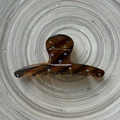 Detail of amber tortoiseshell hair claw clip with colorful rhinestones on wood base - Brown