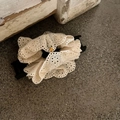 Close-up of white lace scrunchie with embroidered eyelet details and a golden charm - Black and White Splicing Lace Large Hair Claw (With Gold Metal Tag)