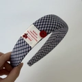 Detailaufnahme eines karierten Haarreifens mit rotem Knopf und Kirsch-Anhänger Dekor - Karo Stirnband