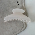 Dettaglio della pinza per capelli color crema lucido su sfondo di tessuto in lino beige - Bianco