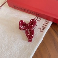 Detailed view of a vintage dark red bow hair clip with white polka dots on fabric - Bowtie