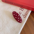 Dettaglio di un fermaglio per capelli vintage rosso a pois su elegante tessuto di lino - Stile Ovale Largo