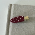 Dettaglio del fermaglio bordeaux a pois con base in metallo dorato e finitura lucida - Clip Senza Segni