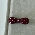 Detail of red polka dot bow hair clip with a glossy finish on a textured fabric - Bowknot Style