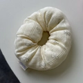 Close-up of beige pointelle scrunchie with grey bow patterns and floral logo label - Cream Yellow Bow Style