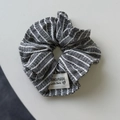 Gros plan sur chouchou en tissu à rayures grises avec texture tissée et étiquette - Chouchou Rayé Gris