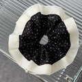 Close-up of oversized black and white polka dot scrunchie with ruffled trim and chiffon texture - Black