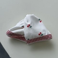 Detail of soft white cotton hair tie featuring red cherry patterns and lace edges - Triangle