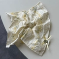 Detalle de coletero floral con borde de encaje, lazo verde y etiqueta de Hand Made - Coletero Pañuelo Amarillo