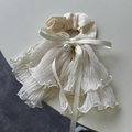 Detail eines eleganten beigen Satin-Haargummis mit Chiffon-Lagen und weißen Perlen - Cremeweiß Schleife Haargummi