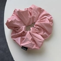 Detail view of pink cream-colored soft leather scrunchie with a Hand Made label - Pink