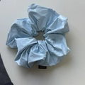 Detail of light blue glossy faux leather scrunchie with a black Hand Made label - Blue