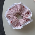 Détail d'un chouchou à carreaux roses avec motif cerise et bordure en dentelle blanche - Style Broderie Cerise Dentelle / Style Dentelle Rose
