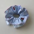 Macro detail of striped scrunchie featuring red cherry embroidery and pink wavy edges - Blue Plaid Scrunchie