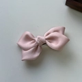 Detalle de una pinza para el pelo con lazo de satén rosa claro sobre una superficie marfil - Rosa