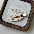 Detailansicht der Vintage-Haarklammer mit Blumenmuster auf einem Holztablett - Rosenrot Blumen Entenschnabelklemme
