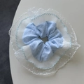 Detail eines blau karierten Haargummis mit weißer Spitze und gepunktetem Netz - Blau