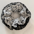 Détail d'un chouchou à carreaux avec broderie de dentelle florale et texture délicate - Noir