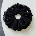 Detailed close-up of a pleated black scrunchie with elegant pearls and small ribbon bows - Black