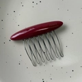 Dettaglio di pettine in acetato rosso con dieci denti in metallo argento e scritte dorate - Rosso
