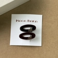 Gros plan sur deux barrettes ovales en acétate écaille avec élégant logo doré - Paire Brune
