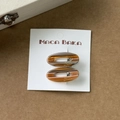 Détail de deux barrettes ovales évidées en acétate ambré sur une carte d'exposition - Paire Café
