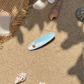 Surfboard hair clip with blue ocean waves and gold shell decor on sandy beach - Blue Shell