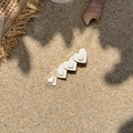 Pinza para el pelo con cinco corazones de acetato crema sobre fondo de arena de playa - Corazón Beige