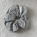 Nahaufnahme eines gestreiften Haargummis mit Made in Korea Etikett auf weißem Stoff - Scrunchie / Weiß Gestreift