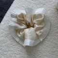 Detail of silk satin scrunchie with white pleated organza trim on soft texture - Champagne
