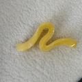 Gros plan d'une pince à cheveux jaune en forme de S avec texture marbrée sur tissu peluche - Vague Jaune