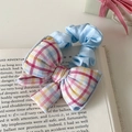 Süßer blauer Haargummi mit Schleife und Karomuster auf Vintage Buchhintergrund - Blaue Schleife
