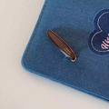Dettaglio di un fermaglio per capelli in acetato ambrato fatto a mano su tessuto denim - Marrone