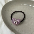 Detailansicht eines Herz-Haargummis aus Acetat mit Schleife, Strass und goldenem Logo - Rosa