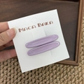 Detalle de dos pinzas metálicas ovaladas para el pelo en color lavanda sobre tarjeta blanca - Morado