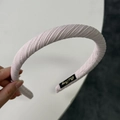 Dettaglio del cerchietto in tessuto plissettato rosa con imbottitura ed etichetta dorata - Rosa