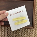 Primer plano de dos pinzas para el cabello ovaladas amarillas brillantes en tarjeta - Amarillo