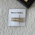 Close-up of two amber acetate hair clips with gold lettering on white faux fur background - Champagne (Pair) / Beige Apricot