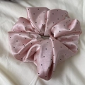 Detail of pink satin polka dot scrunchie showing smooth texture and elegant folds - Pink